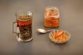 Glass of hot tea in an antique silver cup holder and a jar of pear jam on a gray wooden table. Minimalism. Royalty Free Stock Photo