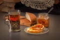 Glass of hot tea in an antique silver cup holder, a piece of rustic bread with pear jam and a jar of jam Royalty Free Stock Photo