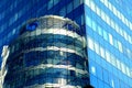 Glass house, high-rise office building, modern skyscraper in which round glass tower is reflected. Tall blue apartment building