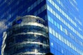 Glass house, high-rise office building, modern skyscraper in which round glass tower is reflected. Tall blue apartment building