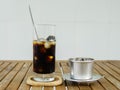 Glass of Ice coffee & Vietnamese traditional coffee filter on wooden table in day light