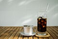 Glass of Ice coffee & Vietnamese traditional coffee filter on wooden table in day light Royalty Free Stock Photo