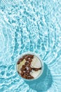 Glass of ice cubes with coffee beans and milk isolated in rippled water. Cold fresh coffee concept. Summer morning drink idea. Royalty Free Stock Photo