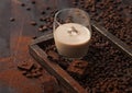 Glass with ice cubes of Irish cream baileys liqueur in wooden tray with coffee beans and powder with dark chocolate on dark wood Royalty Free Stock Photo