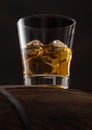 Glass with ice cubes of scotch whiskey on top of wooden barrel and black Royalty Free Stock Photo