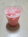 a glass of ice milk mixed with red syrup and a clear white glass