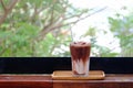 A glass of iced chocolate soft drinks with a steel straw in a wooden tray with an orange flower on wood balcony Royalty Free Stock Photo