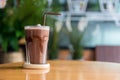 A glass of iced chocolate on table. A glass of Iced Cocoa cool drink served on table. Iced cocoa drink on a wooden table at a cafe