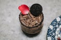 A glass of Iced Cocoa decorated with chocolate cookie and pink flower cool drink served on table.