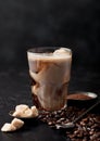 Glass with iced coffee with beans and cane sugar with ground coffee and long spoon on black background Royalty Free Stock Photo