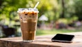 A glass of iced coffee and a cell phone on a table