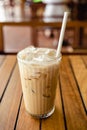 Glass of iced coffee with paper straw on wooden table Royalty Free Stock Photo