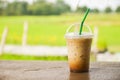 glass of iced coffee on wooden balcony with green nature background