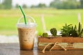 glass of iced coffee on wooden balcony with green nature background