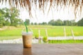 glass of iced coffee on wooden balcony with green nature background