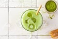 Glass of iced green matcha latte with a straw on white tile background. top view Royalty Free Stock Photo