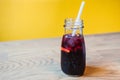 A glass of iced hibiscus tea with slices of lime, and drinking straw, on yellow background Royalty Free Stock Photo