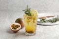 A glass of Iced passion fruit soda with lemon and passion fruit half slice on grey background, a healthy summer drink