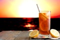 Glass of iced tea against a vibrant ocean sunset background Royalty Free Stock Photo