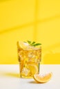 A glass of iced tea with lemon and mint on a yellow and white background with a shadow from the window Royalty Free Stock Photo