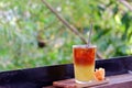 A glass of iced tea soft drink in a wooden tray with an orange flower on wood balcony Royalty Free Stock Photo