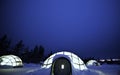 A glass igloo in the snow at night.