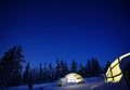 A glass igloo in the snow at night.