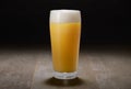 A glass of India Pale Ale, hazy unfiltered juicy draft beer on wooden surface and black background