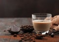 Glass of Irish cream baileys liqueur with coffee beans and powder with dark chocolate and brown cloth on dark wood background Royalty Free Stock Photo