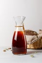 A glass jag with dark rye kvass or beer. On a light wooden background, a basket with rye bread in the background