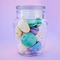 Glass jar, beach stones or rocks on table in studio isolated on a purple background. Beauty, art and variety of colorful Royalty Free Stock Photo