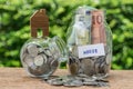 Glass jar bottles labeled as House with full of coins and banknotes with miniature house as Home, Property or Mortgage Royalty Free Stock Photo