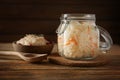 Glass jar and bowl with delicious sauerkraut on wooden table Royalty Free Stock Photo