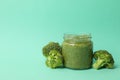 Glass jar broccoli puree on mint background