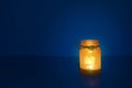 Glass jar with candle flame in the shape of a heart in the dark Royalty Free Stock Photo