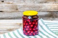 Glass jar with canned cherries fruits. Preserved fruits concept, canned fruits compote isolated in a rustic composition Royalty Free Stock Photo