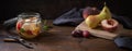 Glass jar with canned fruits and fresh pears, peaches and plums on a dark rustic wooden table, moody vintage still life style in