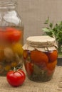 Glass jar of canned tomatoes and fresh tomatoes