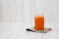 Glass jar of carrot smoothie on white wooden surface, side view. Closeup. Space for text