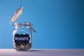 Glass jar with coins with chalk tag Donate on a blue background. Donation and charity concept. Copy space Royalty Free Stock Photo