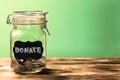 Glass jar with coins with chalk tag Donate on a green background. Donation and charity concept. Copy space Royalty Free Stock Photo