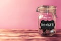 Glass jar with coins with chalk tag Donate on a pink background. Donation and charity concept. Copy space Royalty Free Stock Photo