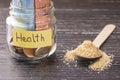 Glass jar with coins and euro banknotes with the inscription HEALTH. A handful of germinated wheat seeds Royalty Free Stock Photo