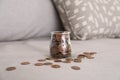 Glass jar with coins on grey sofa