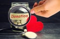Glass jar with coins, heart and stethoscope and the inscription `Donation`. Medicine concept. blood transfusion, health care. Volu