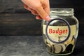 Glass jar with coins and the inscription `Budget`. The concept of accumulating money in the family budget. Family Insurance. Distr