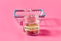 Glass jar with coins and inscription business solution near empty market basket lies on pink Royalty Free Stock Photo