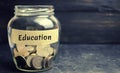 Glass jar with coins and the inscription `Education`. The concept of education for yourself or children. Accumulation of money for