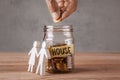 Glass jar with coins and an inscription is house and symbol of family or couple. Man holds coin in hand Royalty Free Stock Photo