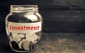 Glass jar with coins and the inscription ` Investment `. Investing in a new business project or real estate. Concept of economic f